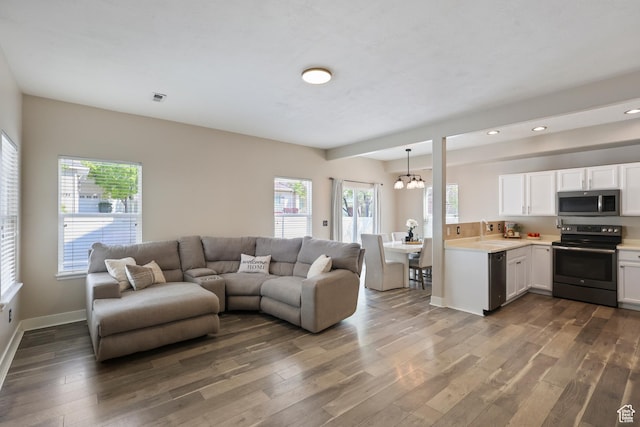 6785 W Callery Ln S, West Jordan, UT 84081 - living room featuring recessed lighting, plenty of natural light, wood finished floors, and a notable chandelier