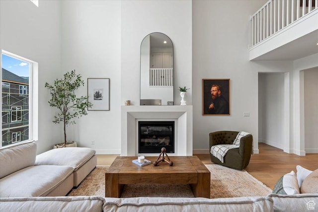 242 W Hillcrest Dr Unit 6, Spanish Fork, UT 84660 - living area featuring baseboards, a high ceiling, a glass covered fireplace, and wood finished floors