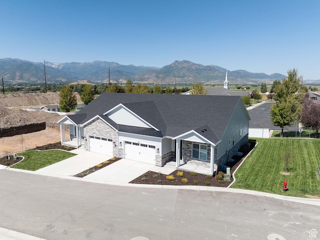 ranch-style home featuring an attached garage, a mountain view, stone siding, and concrete driveway