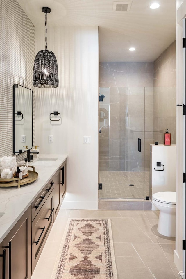 full bath with double vanity, toilet, tile patterned floors, a sink, and a stall shower
