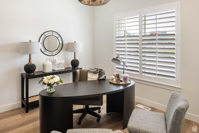 office space featuring baseboards, visible vents, and wood finished floors