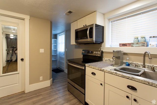 465 S Main St, Providence, UT 84332 - kitchen with a sink, light wood-style flooring, stainless steel appliances, white cabinetry, and visible vents