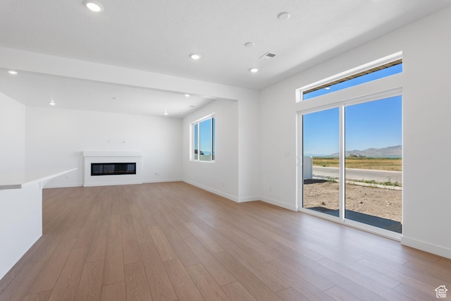 894 S 1100 W, American Fork, UT 84003 - unfurnished living room with light wood finished floors, a mountain view, baseboards, and a glass covered fireplace