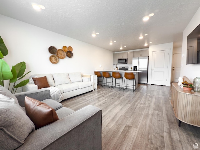 living area with recessed lighting, a textured ceiling, and light wood-style floors