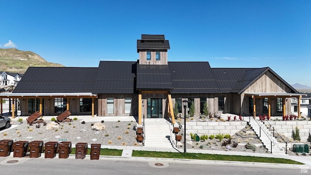 rear view of house featuring a standing seam roof, a mountain view, metal roof, and stairway