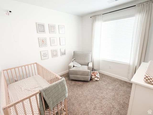 carpeted bedroom featuring baseboards, a nursery area, and visible vents