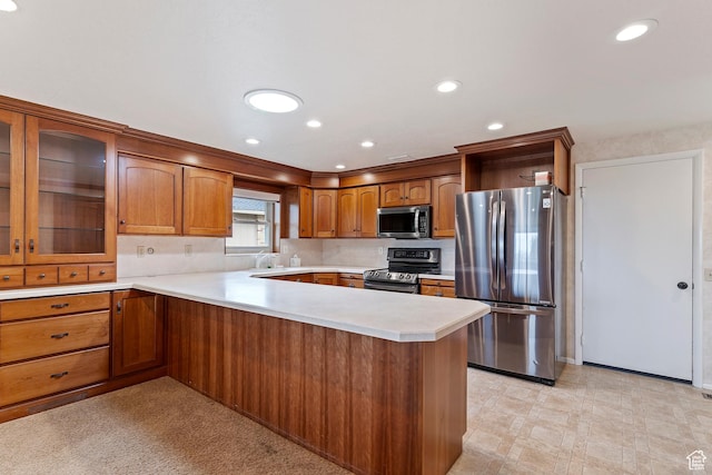 731 W 3750 N, Pleasant View, UT 84414 - kitchen with brown cabinetry, a peninsula, glass insert cabinets, light countertops, and stainless steel appliances