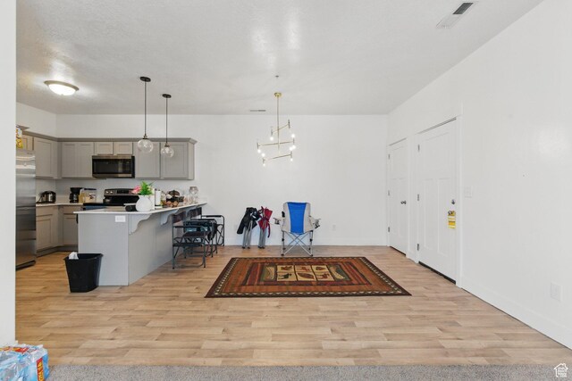 3647 W 1530 N Unit Hh204, Lehi, UT 84043 - kitchen featuring appliances with stainless steel finishes, a kitchen breakfast bar, gray cabinets, light wood-style flooring, and visible vents