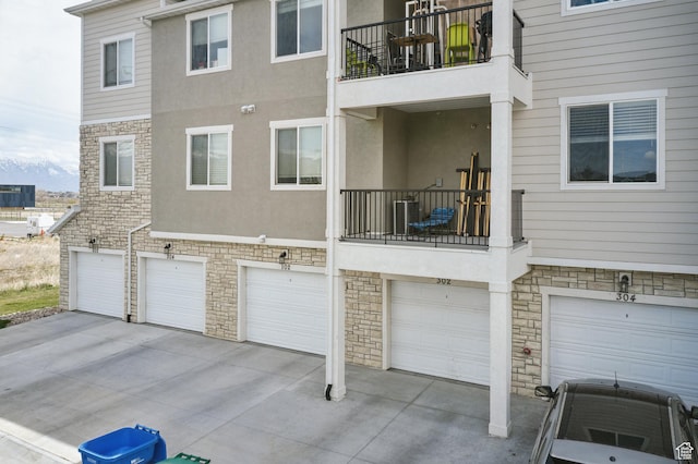 3647 W 1530 N Unit Hh204, Lehi, UT 84043 - rear view of house with driveway, a garage, cooling unit, stone siding, and stucco siding