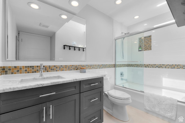 full bathroom featuring vanity, toilet, shower / bath combination with glass door, tile walls, and recessed lighting