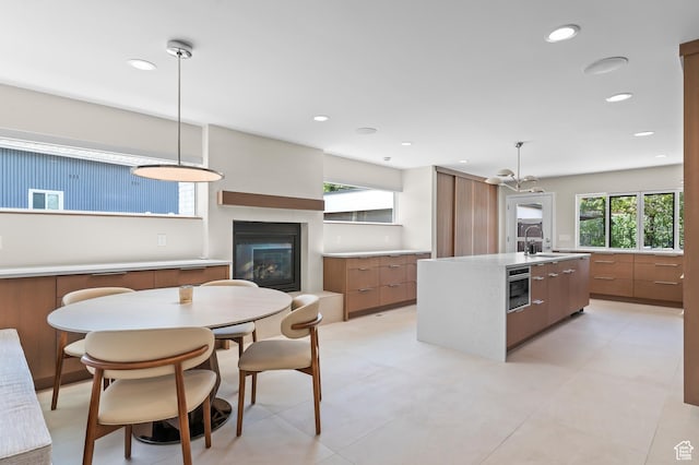 kitchen featuring a sink, a glass covered fireplace, brown cabinetry, and modern cabinets