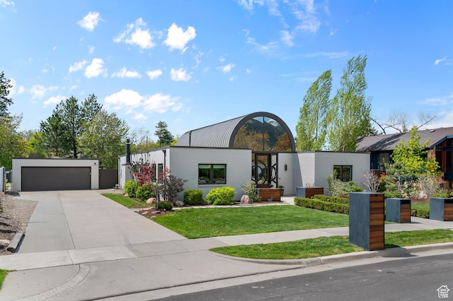 contemporary house with concrete driveway and a front lawn