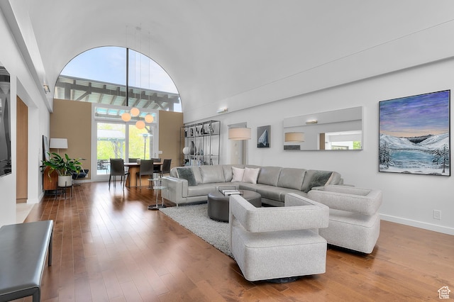 living area featuring baseboards, wood-type flooring, and a towering ceiling
