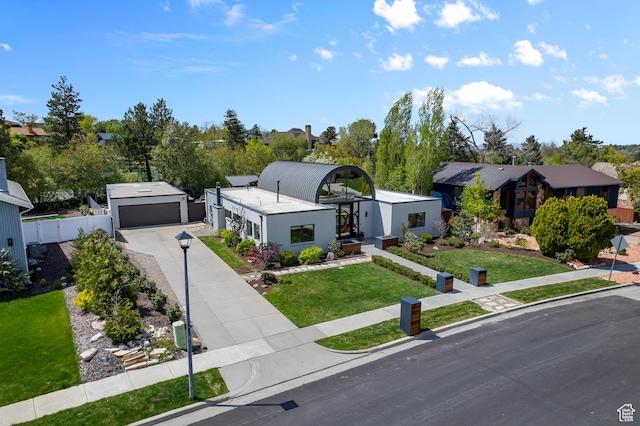 view of front facade featuring a detached garage, fence, concrete driveway, and a front lawn