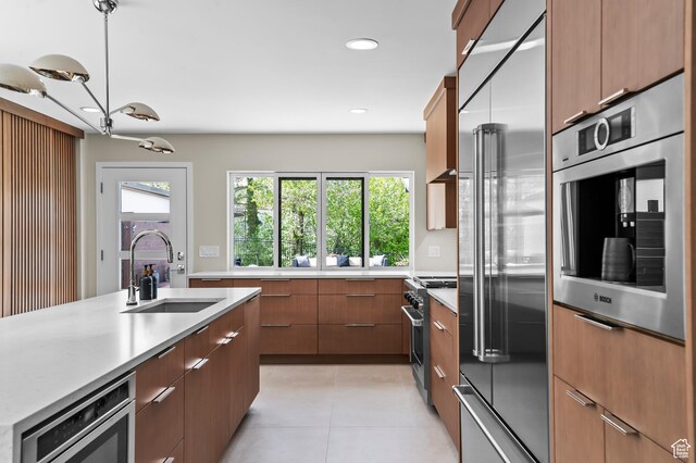 kitchen featuring a sink, built in appliances, light countertops, light tile patterned floors, and modern cabinets
