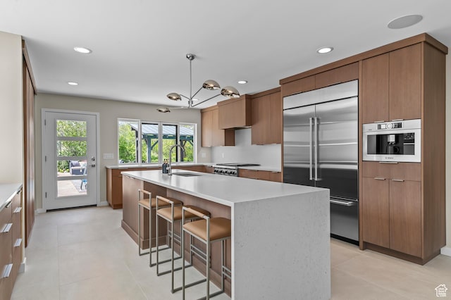 kitchen featuring modern cabinets, recessed lighting, light countertops, built in refrigerator, and a sink