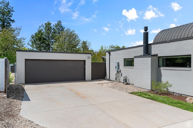 view of side of property with a detached garage, brick siding, fence, and an outdoor structure