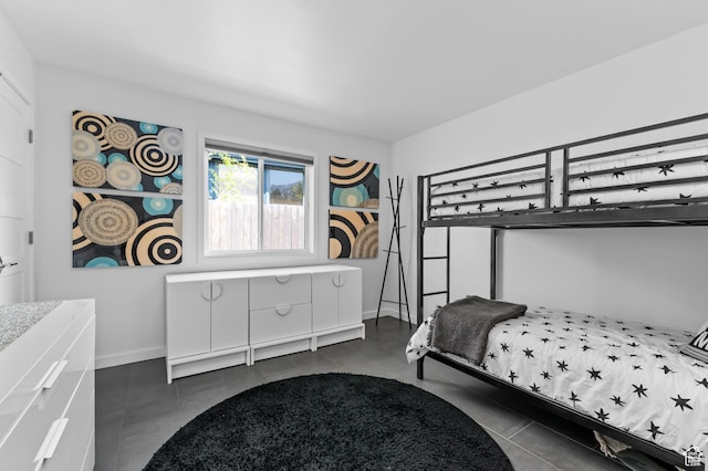 bedroom featuring dark tile patterned floors and baseboards