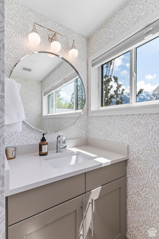 bathroom with vanity, wallpapered walls, and visible vents