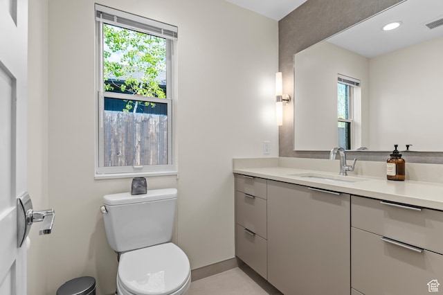bathroom with vanity, baseboards, toilet, and visible vents