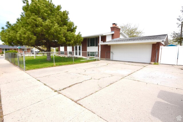3223 S Fairlane St, Magna, UT 84044 - view of front of property with driveway, a chimney, a front yard, a garage, and brick siding