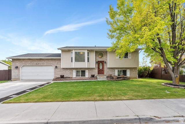 split foyer home with fence, an attached garage, brick siding, a front yard, and driveway