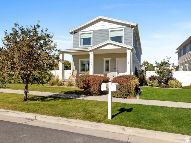 traditional home with a porch, fence, and a front yard