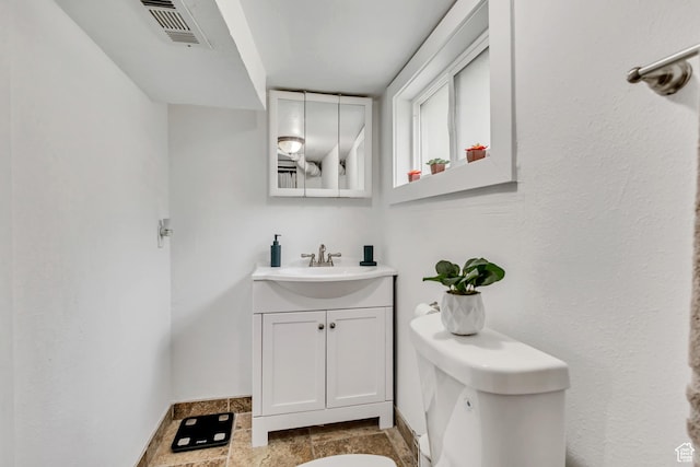 133 E 7th St S, Ogden, UT 84404 - half bath with vanity, toilet, stone finish floor, baseboards, and visible vents