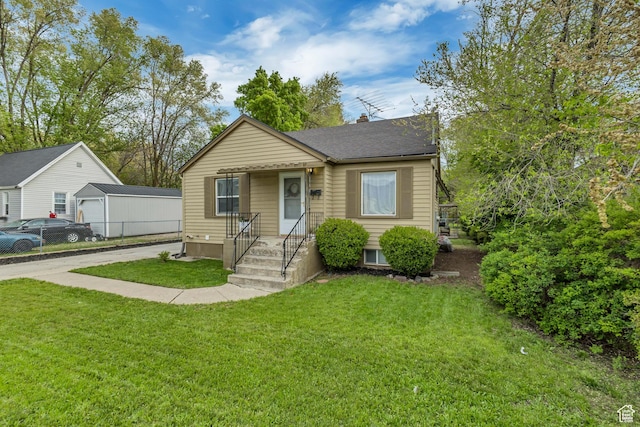bungalow with a shingled roof, concrete driveway, and a front lawn