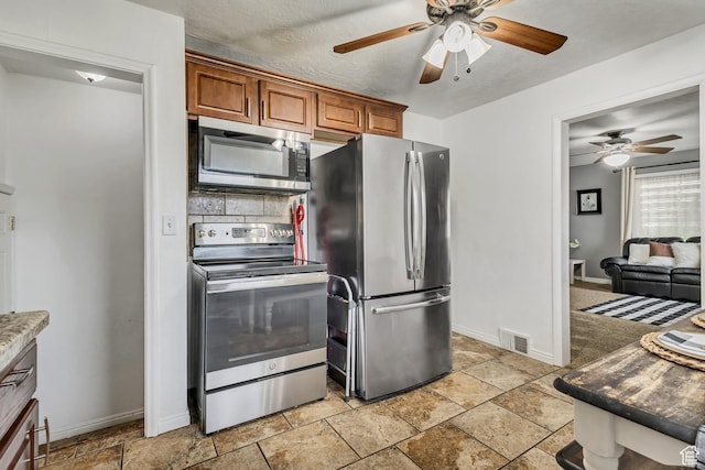 133 E 7th St S, Ogden, UT 84404 - kitchen with visible vents, brown cabinetry, baseboards, ceiling fan, and appliances with stainless steel finishes
