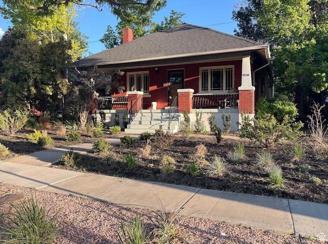 970 E Wilson Ave S, Salt Lake City, UT 84105 - view of front facade featuring covered porch, a chimney, brick siding, and roof with shingles