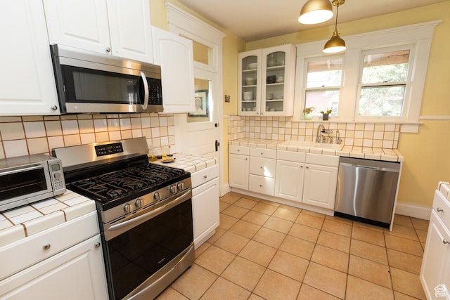970 E Wilson Ave S, Salt Lake City, UT 84105 - kitchen featuring appliances with stainless steel finishes, tile countertops, a sink, and white cabinets