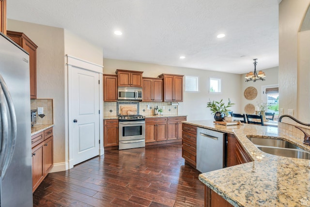 2797 W Fox Hunters Loop, Lehi, UT 84043 - kitchen with appliances with stainless steel finishes, a sink, a chandelier, brown cabinetry, and tasteful backsplash