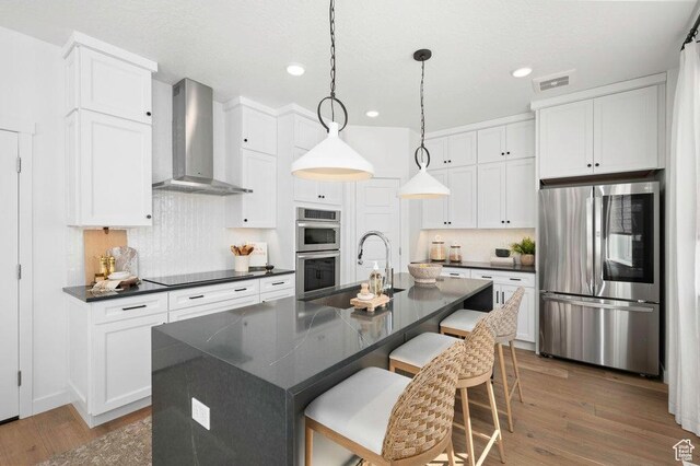 246 E Wasatch Ave Unit 201, Midvale, UT 84070 - kitchen with stainless steel appliances, wall chimney exhaust hood, dark countertops, a sink, and white cabinetry