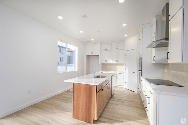 246 E Wasatch Ave Unit 201, Midvale, UT 84070 - kitchen featuring black electric stovetop, a sink, a center island with sink, backsplash, and light wood-style flooring