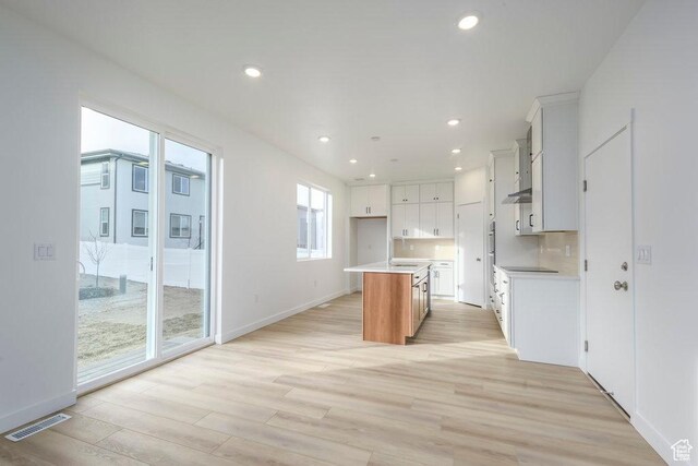 246 E Wasatch Ave Unit 201, Midvale, UT 84070 - kitchen with light wood finished floors, light countertops, recessed lighting, a center island with sink, and wall chimney range hood