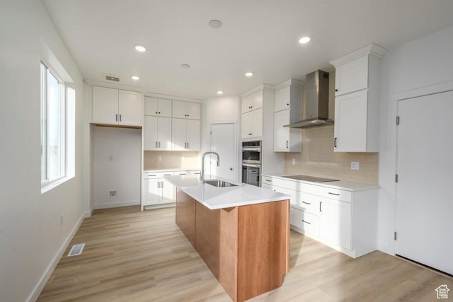 246 E Wasatch Ave Unit 201, Midvale, UT 84070 - kitchen featuring wall chimney exhaust hood, a sink, stainless steel double oven, decorative backsplash, and light wood finished floors