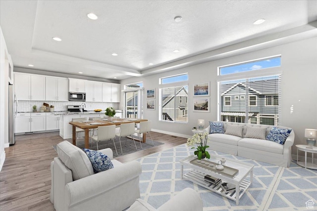 4264 W Abbey Bend Ln, Herriman, UT 84096 - living room featuring light wood-style floors, a raised ceiling, baseboards, recessed lighting, and a textured ceiling