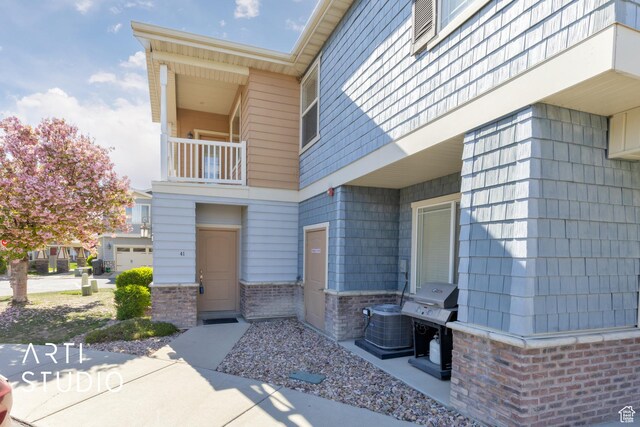 doorway to property featuring brick siding and a balcony