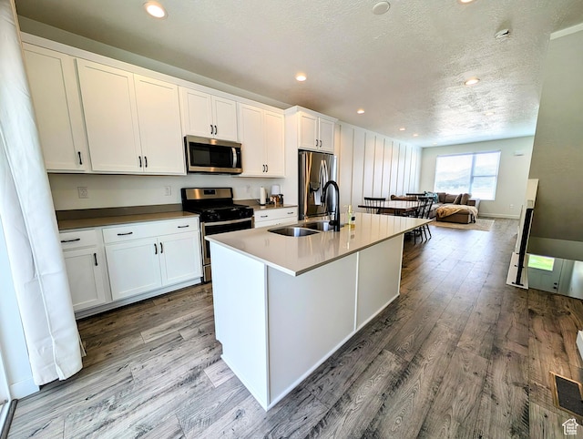 6688 W 11800 S, South Jordan, UT 84009 - kitchen featuring a kitchen island with sink, appliances with stainless steel finishes, wood finished floors, and white cabinets
