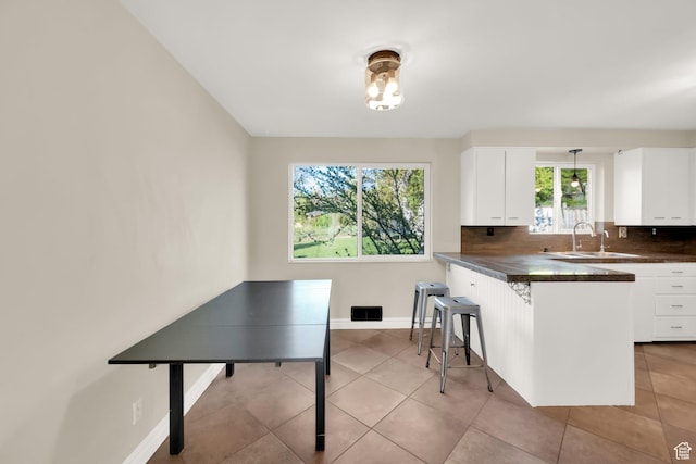 257 E Kingdon S, North Salt Lake, UT 84054 - kitchen featuring a sink, white cabinets, dark countertops, and a kitchen bar