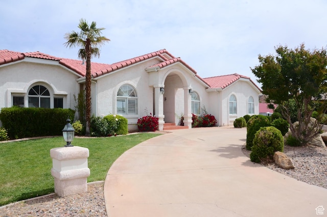 1087 E Fort Pierce Dr, St George, UT 84790 - mediterranean / spanish house featuring a front lawn, stucco siding, a tile roof, and concrete driveway
