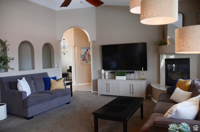 1087 E Fort Pierce Dr, St George, UT 84790 - carpeted living room with arched walkways, a glass covered fireplace, a ceiling fan, baseboards, and a towering ceiling