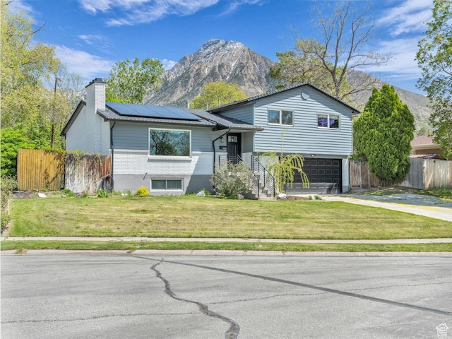 4363 S Butternut Rd E, Holladay, UT 84124 - tri-level home with roof mounted solar panels, fence, a mountain view, and a front lawn