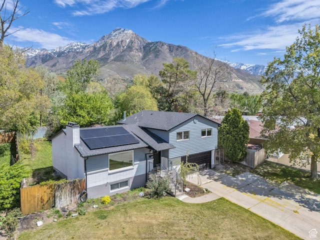 4363 S Butternut Rd E, Holladay, UT 84124 - view of front facade featuring a chimney, a mountain view, roof mounted solar panels, concrete driveway, and an attached garage