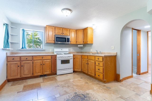 1340 E Oakmont Ln, Fruit Heights, UT 84037 - kitchen with a sink, white range with gas cooktop, stainless steel microwave, arched walkways, and light countertops