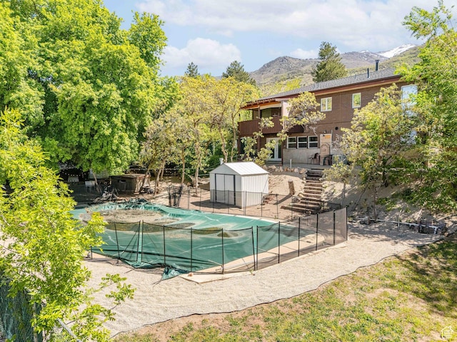 1340 E Oakmont Ln, Fruit Heights, UT 84037 - view of pool with fence, an outdoor structure, a mountain view, a storage unit, and a covered pool