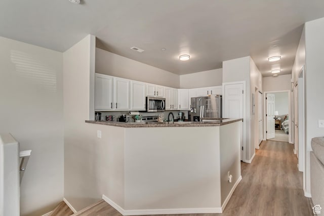 6626 W Ivy Gable Dr S, West Jordan, UT 84081 - kitchen featuring a peninsula, light wood finished floors, appliances with stainless steel finishes, and white cabinetry