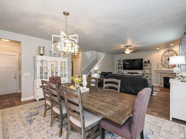 10953 S Kelso Dune Dr, South Jordan, UT 84009 - dining space with a fireplace, ceiling fan with notable chandelier, baseboards, wood finished floors, and stairway