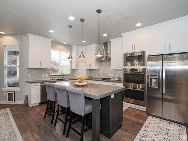 10953 S Kelso Dune Dr, South Jordan, UT 84009 - kitchen with wall chimney range hood, appliances with stainless steel finishes, a sink, white cabinetry, and dark wood-type flooring